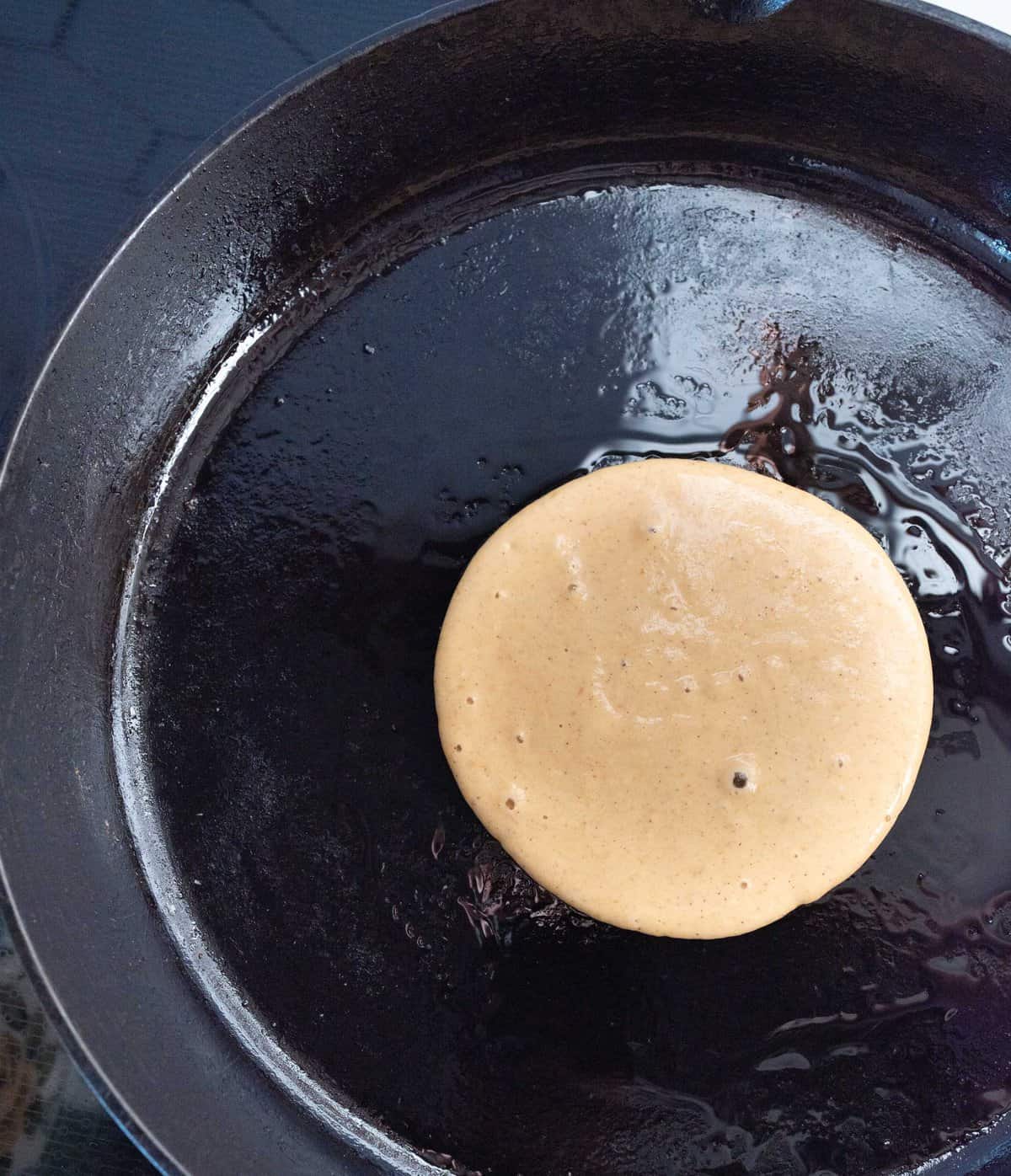 fluffy pumpkin pancakes in process being cooked on cast iron.