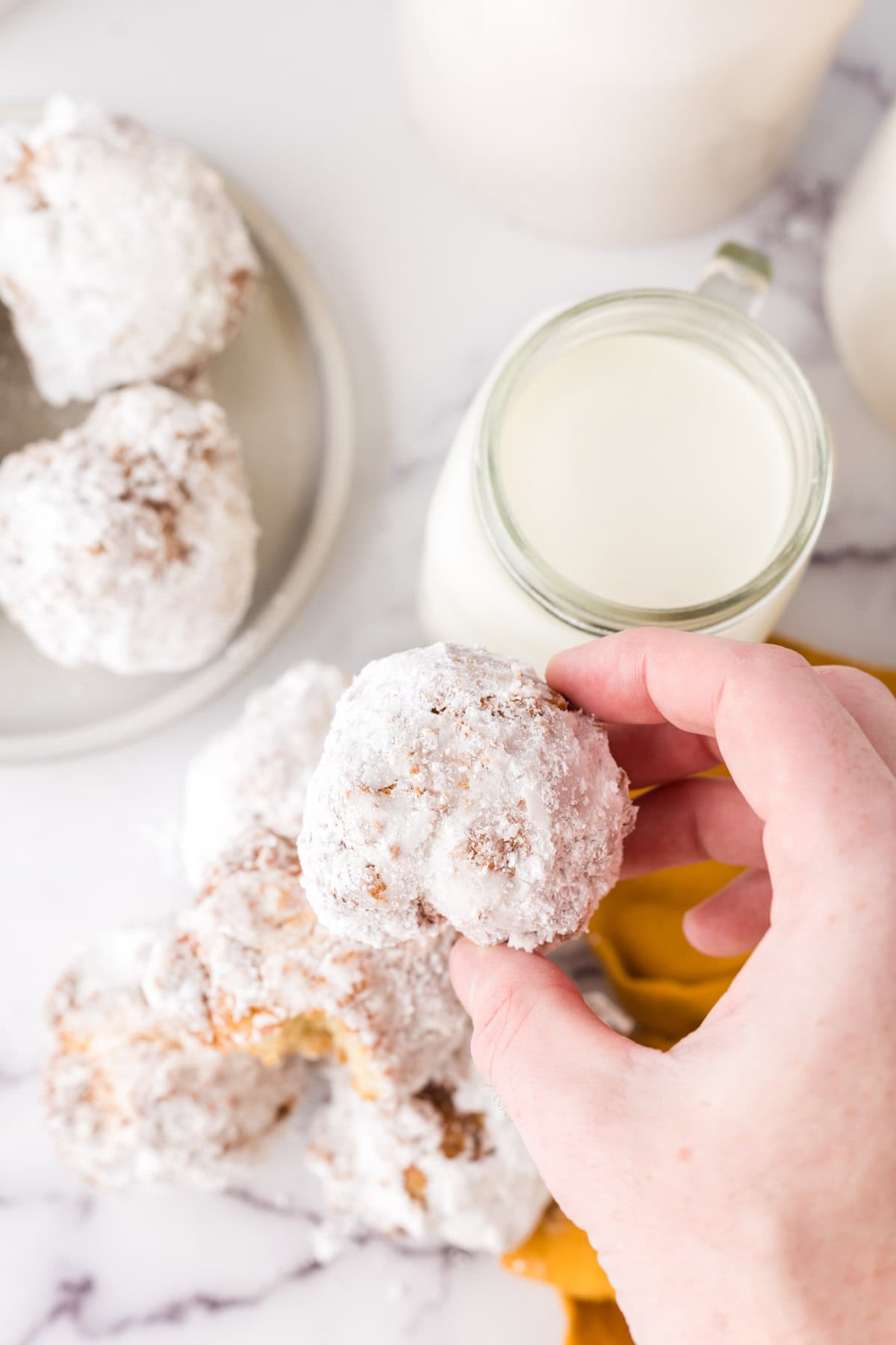 A hand holding a powdered donut hole. 