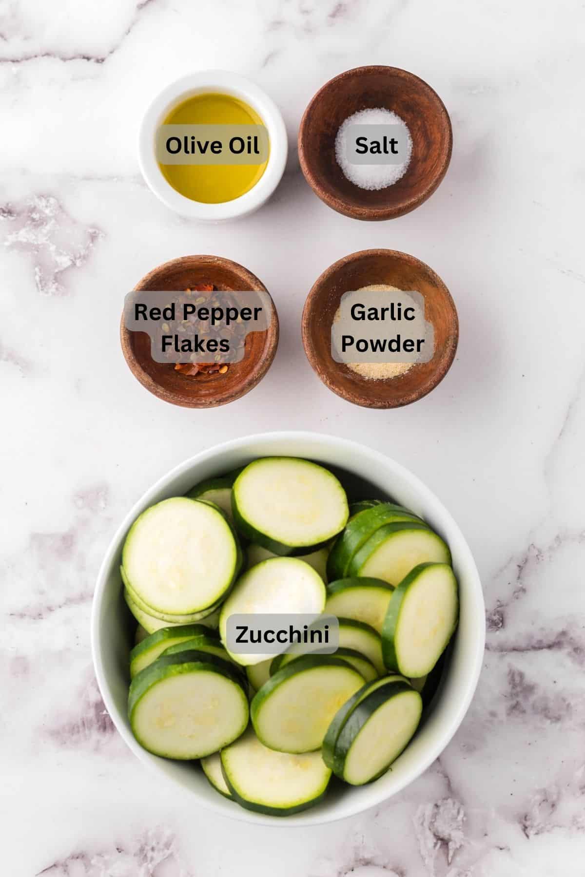portion bowls each with digitally labeled raw ingredients to make air fryer zucchini.