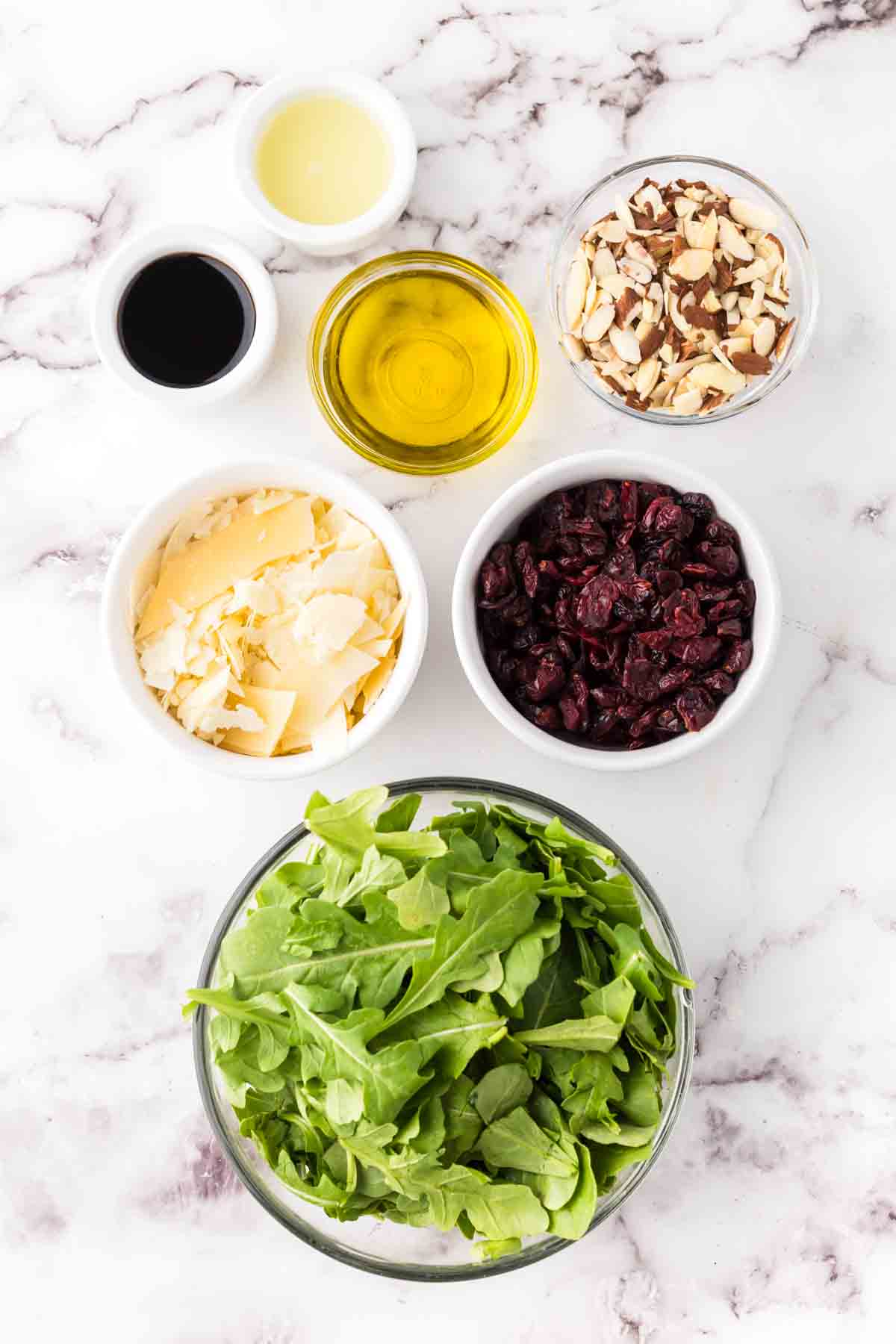 portion bowls each with raw ingredients to make arugula salad.