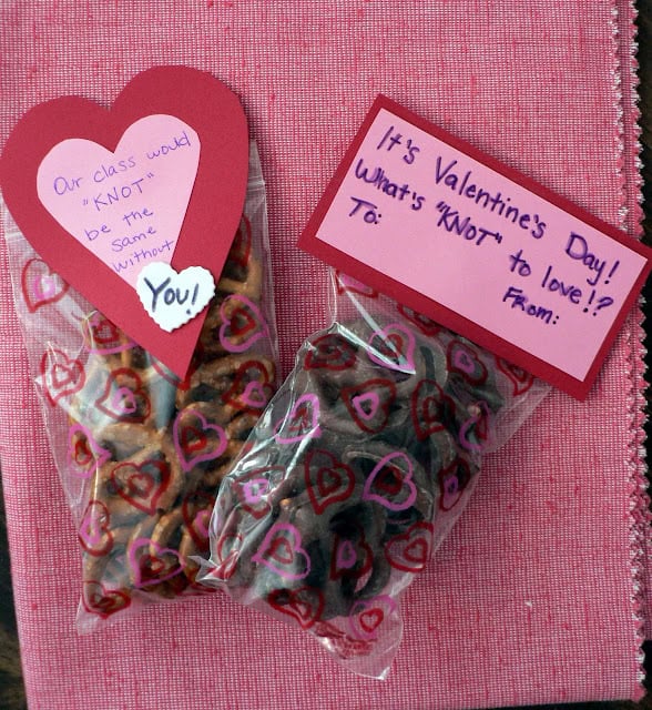 A small clear plastic bag of twist pretzels with a heart-shaped piece of paper that says Our class would KNOT be the same without you and a small clear plastic bag of chocolate-covered pretzels with a note that says It's Valentine's Day what's KNOT to love. 