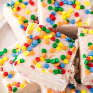 a plate of rainbow sprinkled square pieces of cake batter fudge.