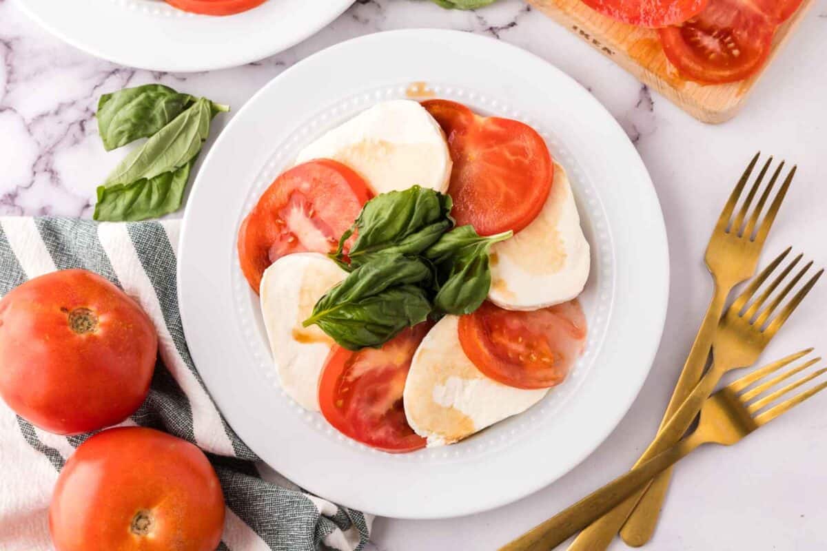 white plate with tomato basil and mozzarella for the caprese salad recipe.