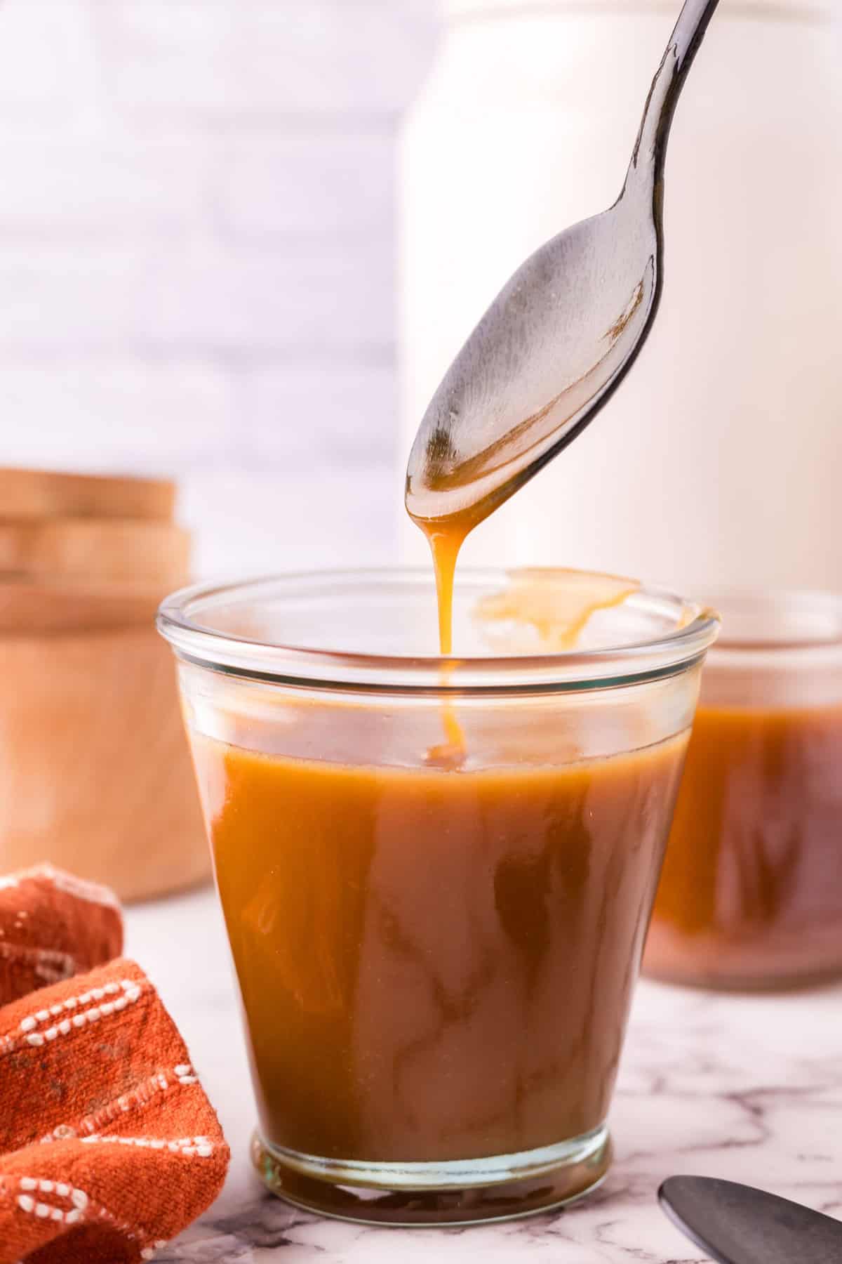 glass jar filled with homemade caramel sauce being spooned out.