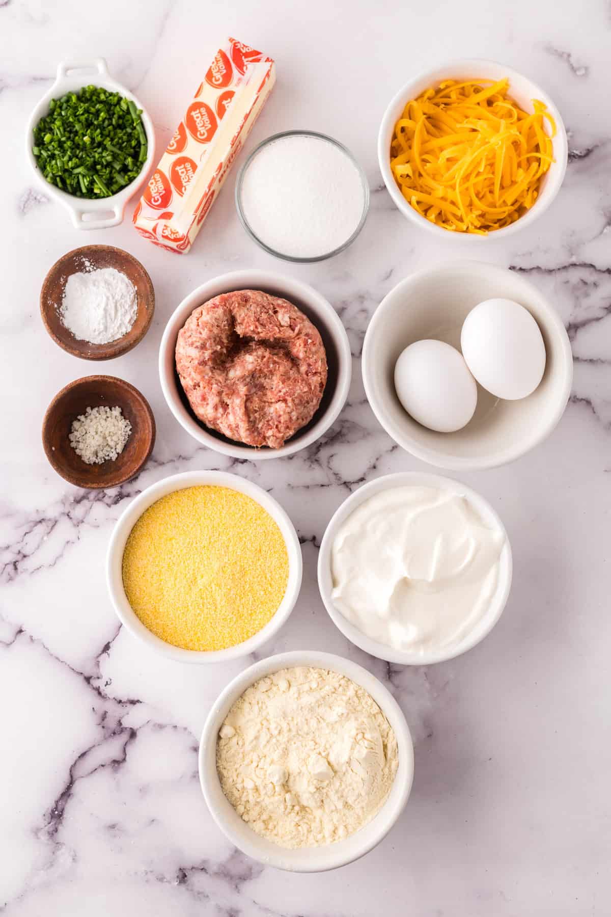 portion bowls each with raw ingredients to make sausage cheddar biscuits.