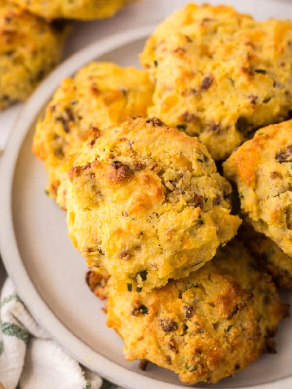 a pile of round golden brown cheddar sausage biscuits.
