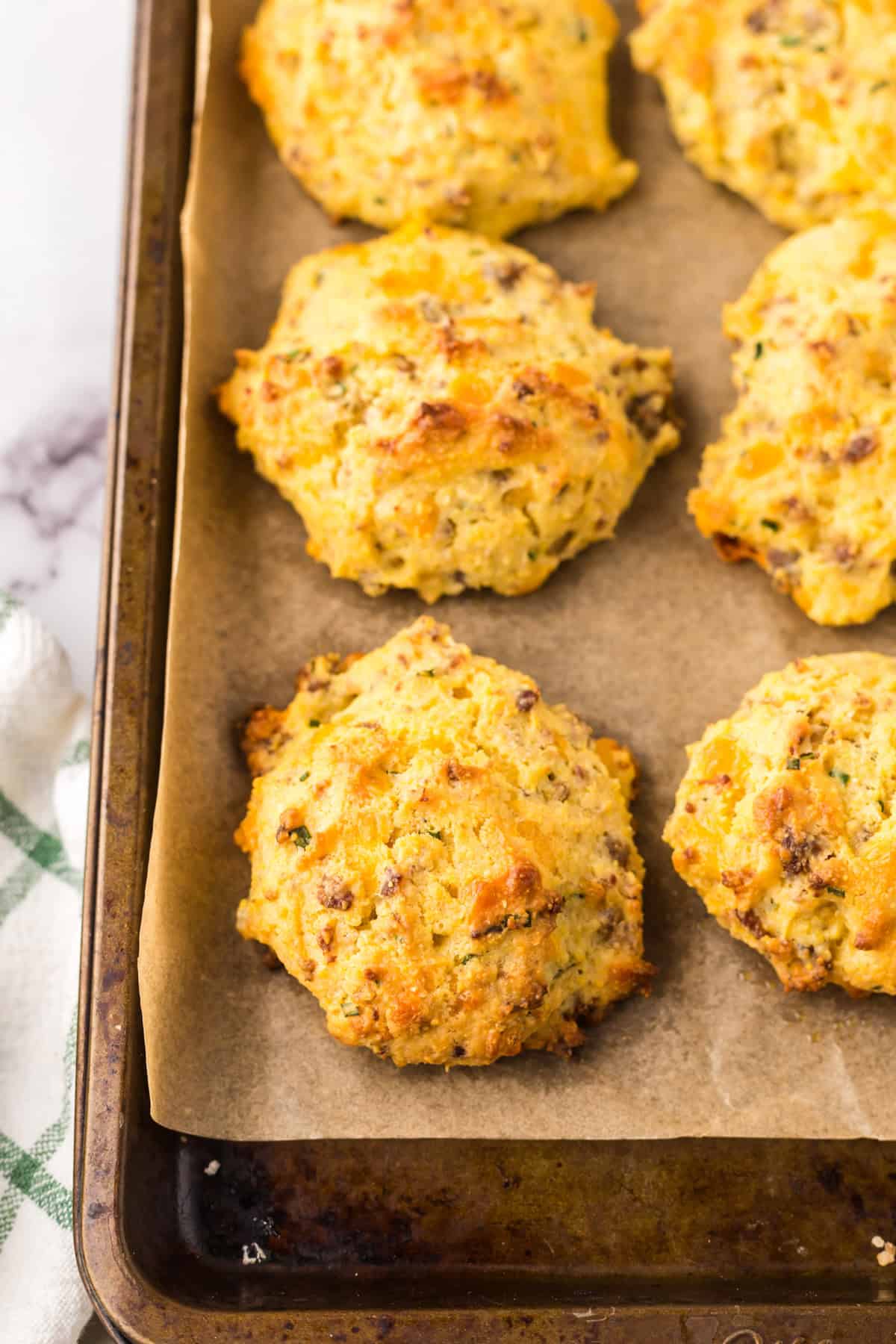 sheet pan with parchment with baked sausage cheddar biscuits.