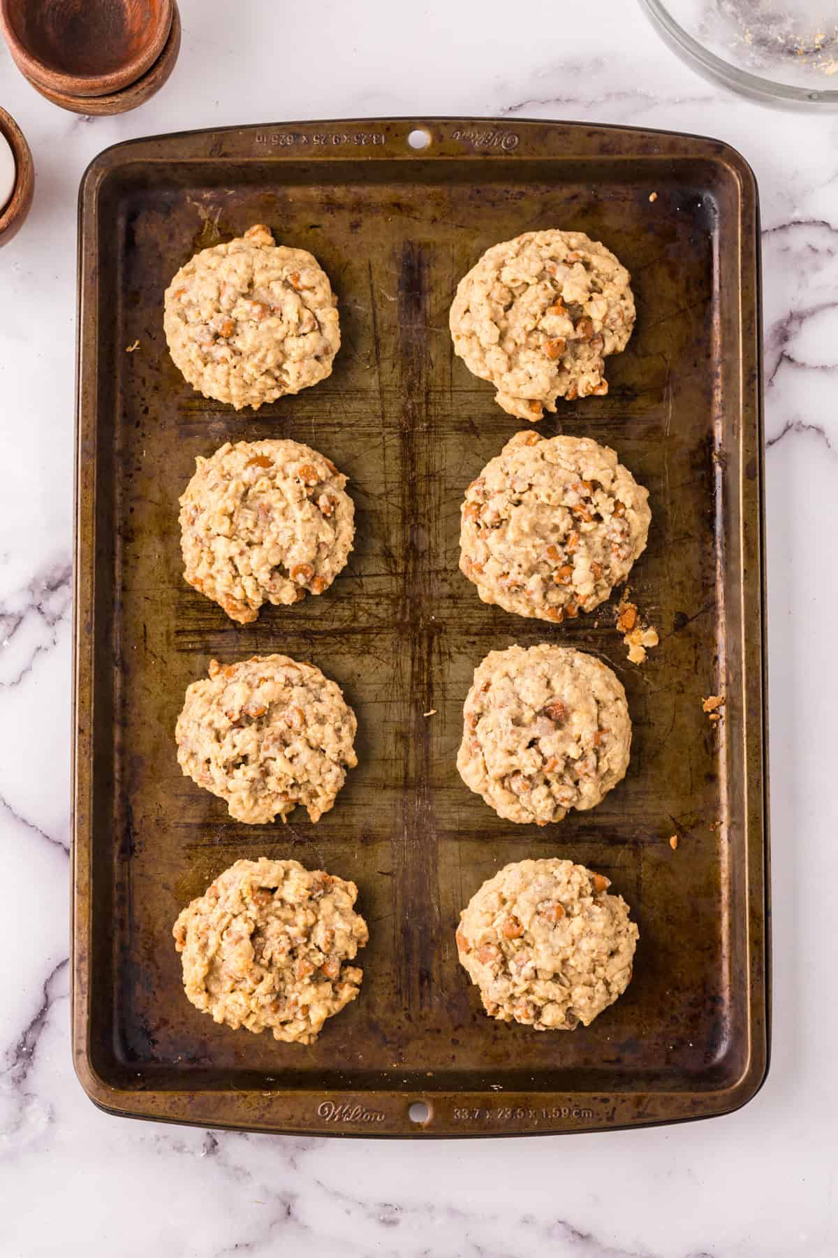 Cinnamon chip oatmeal cookie dough in balls on a cookie sheet.