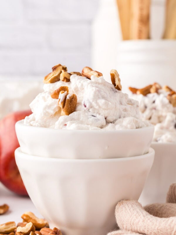 small white portion bowl with dixie salad recipe and walnuts on top.