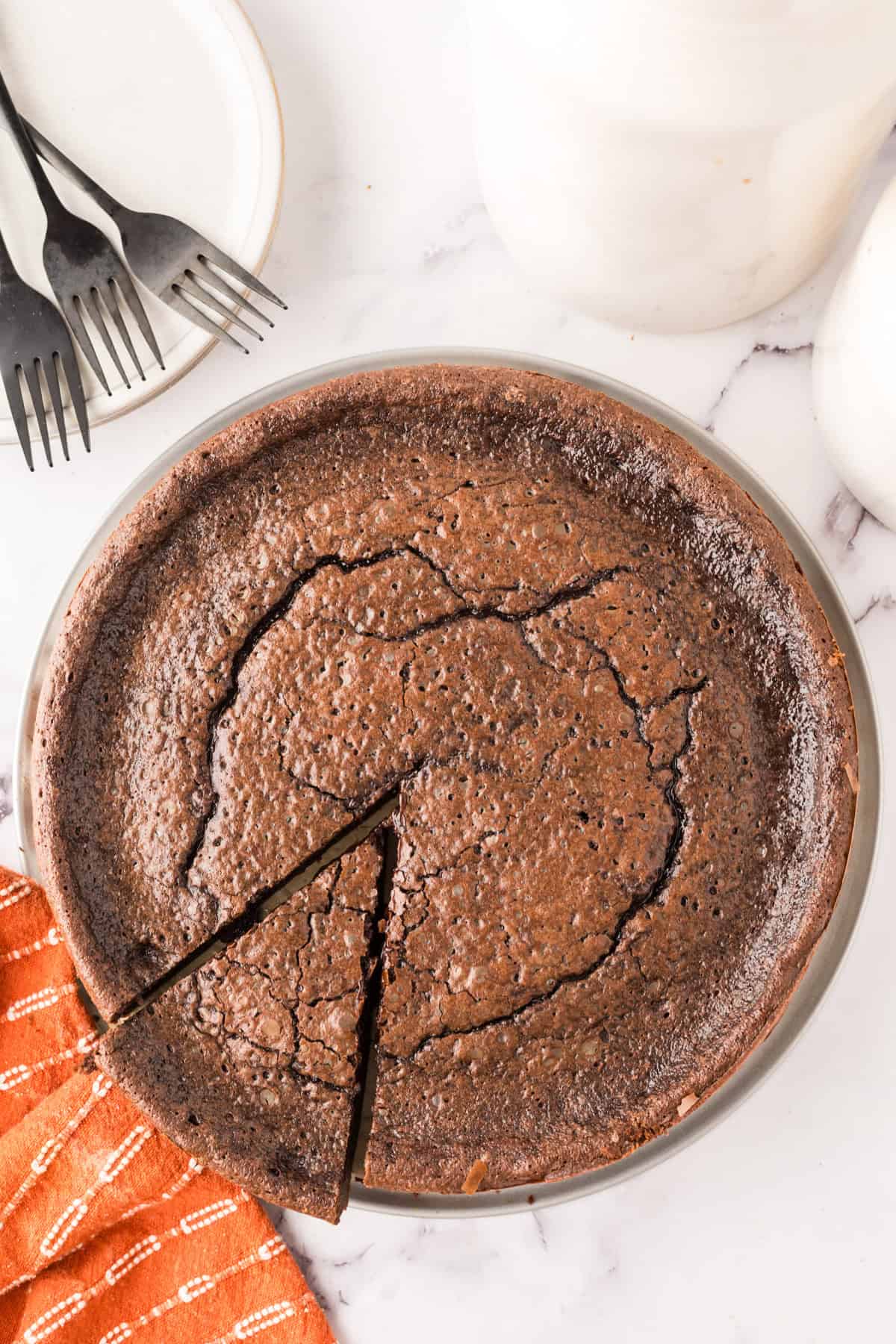 round cake pan with fresh from the oven flourless chocolate cake.
