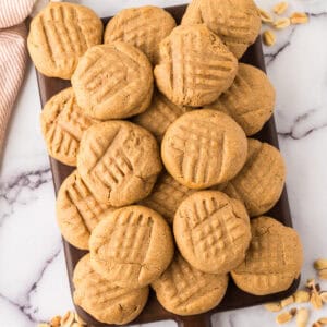 pile of honey peanut butter cookies over a dark wooden chopping board.