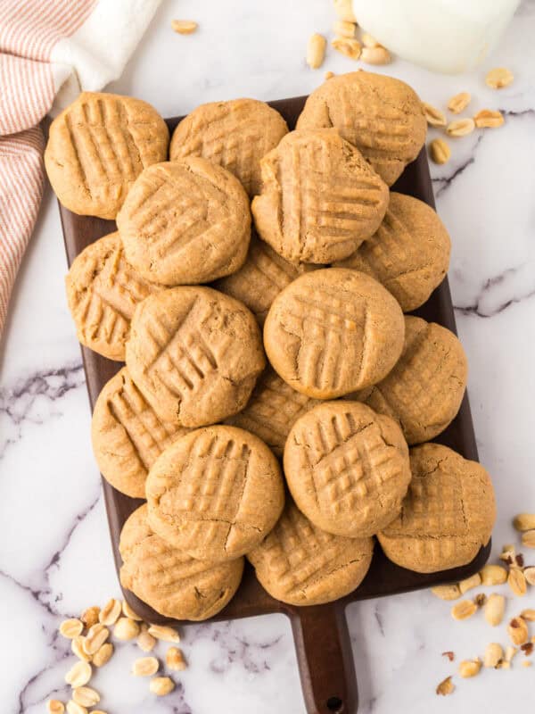 pile of honey peanut butter cookies over a dark wooden chopping board.
