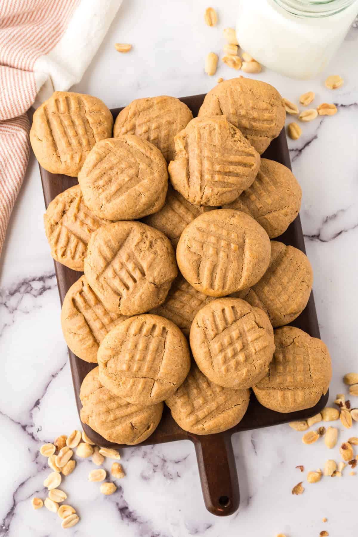 pile of honey peanut butter cookies over a dark wooden chopping board.