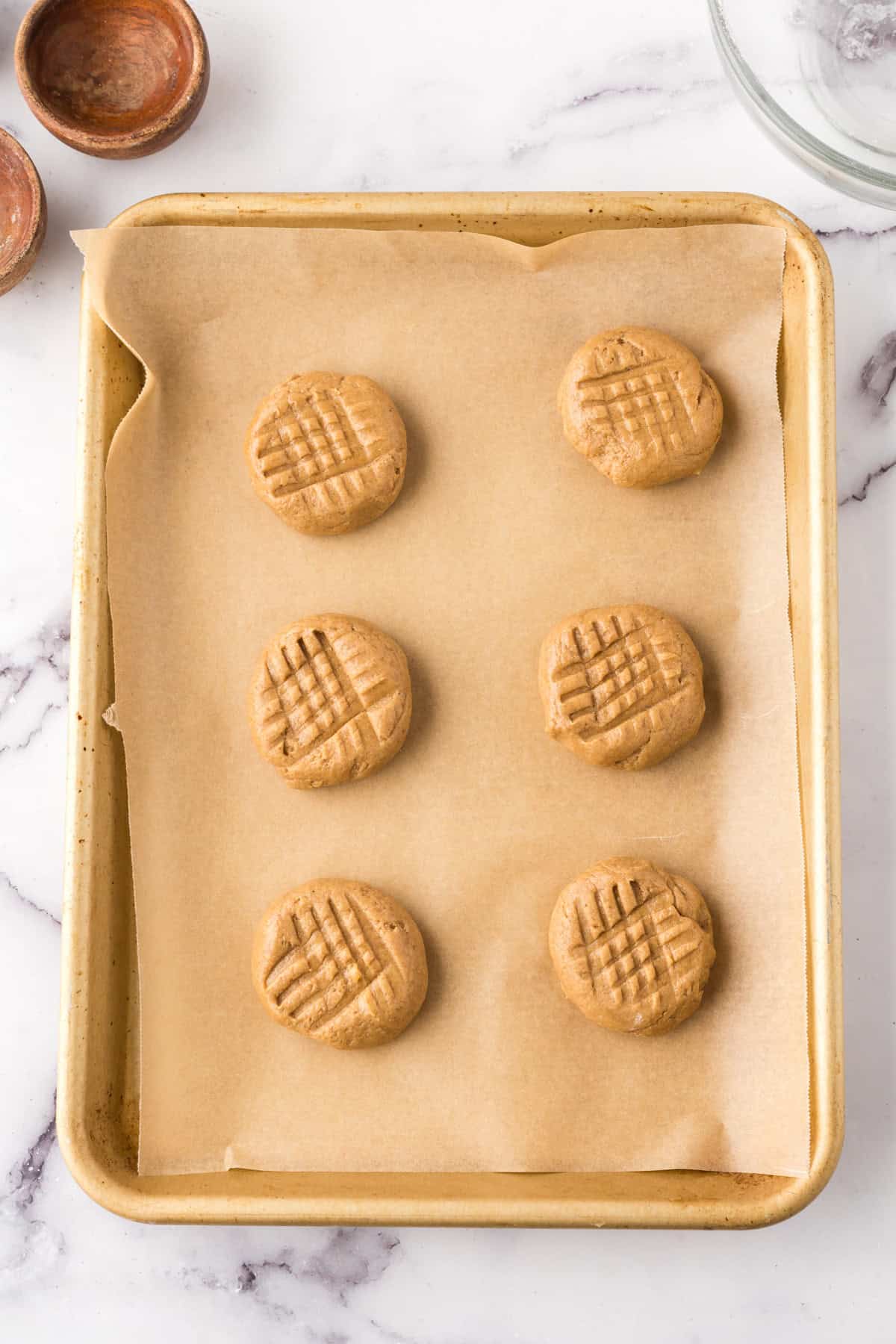 honey peanut butter cookies on a cooking sheet over parchment paper.