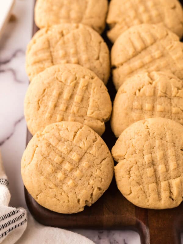 homemade baked peanut butter cookies in rows on a wooden board.