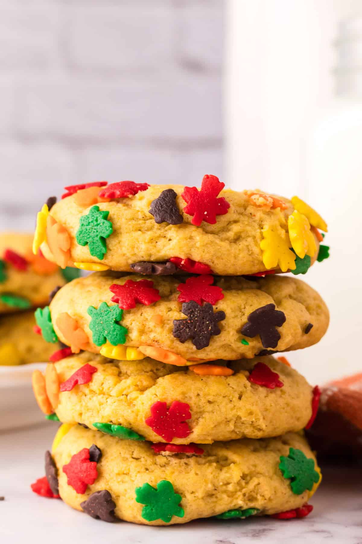a stack of four pumpkin cookies with autumn sprinkles.