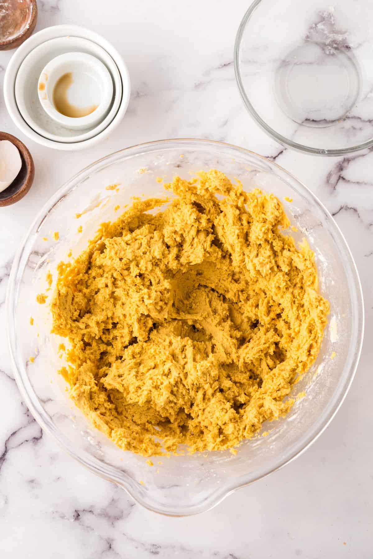 clear mixing bowl in the process of making pumpkin cookie batter.