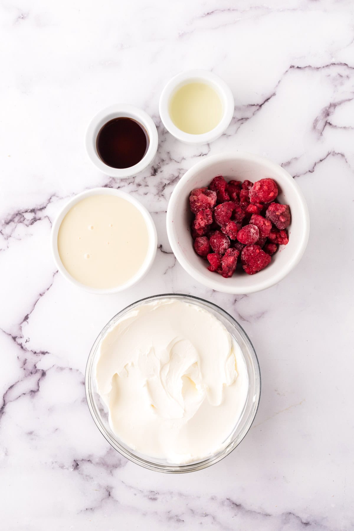 portion bowls each with raw ingredients to make the raspberry cheesecake dip recipe.