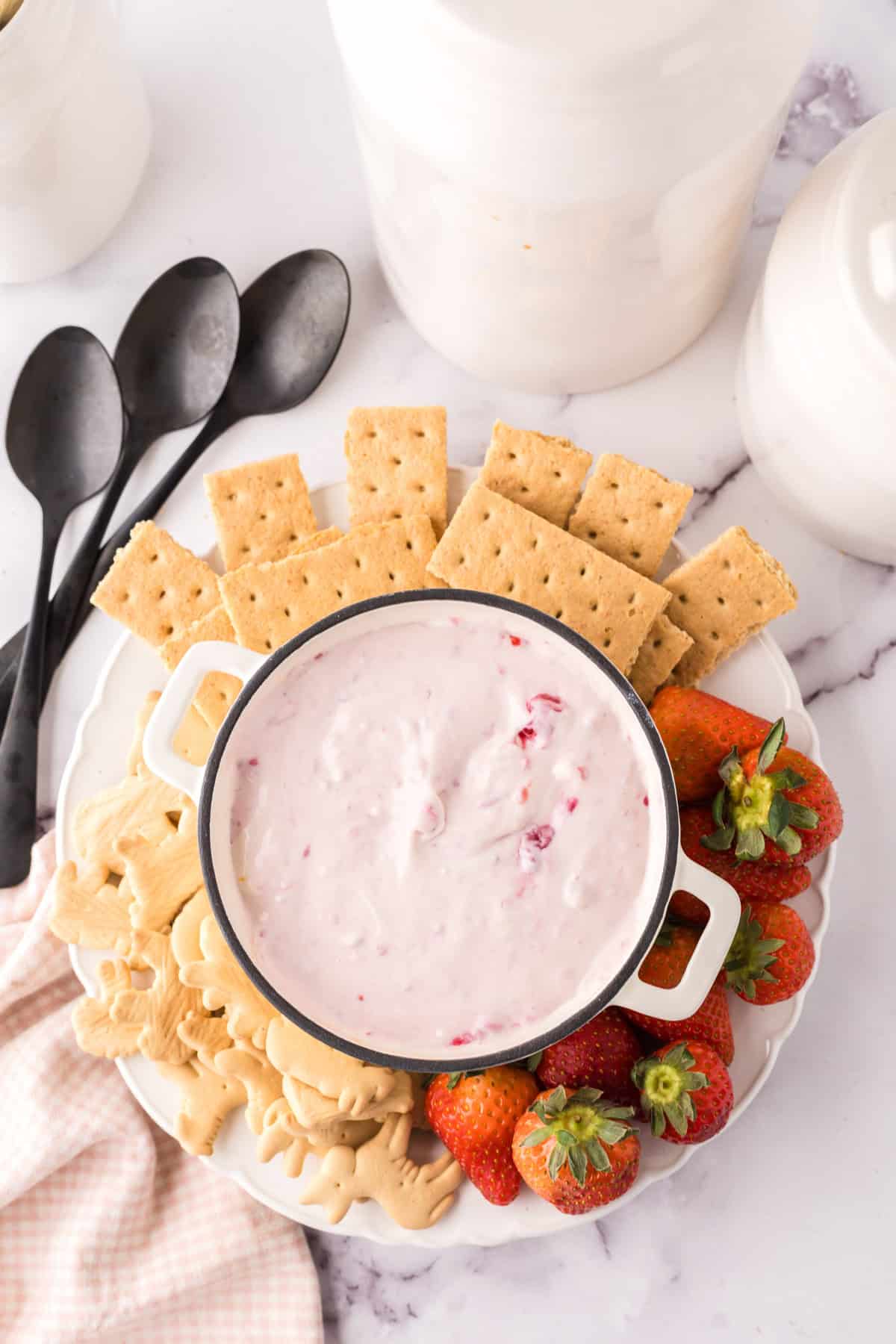 small bowl with crackers and berries around it with the raspberry cheesecake dip recipe inside.