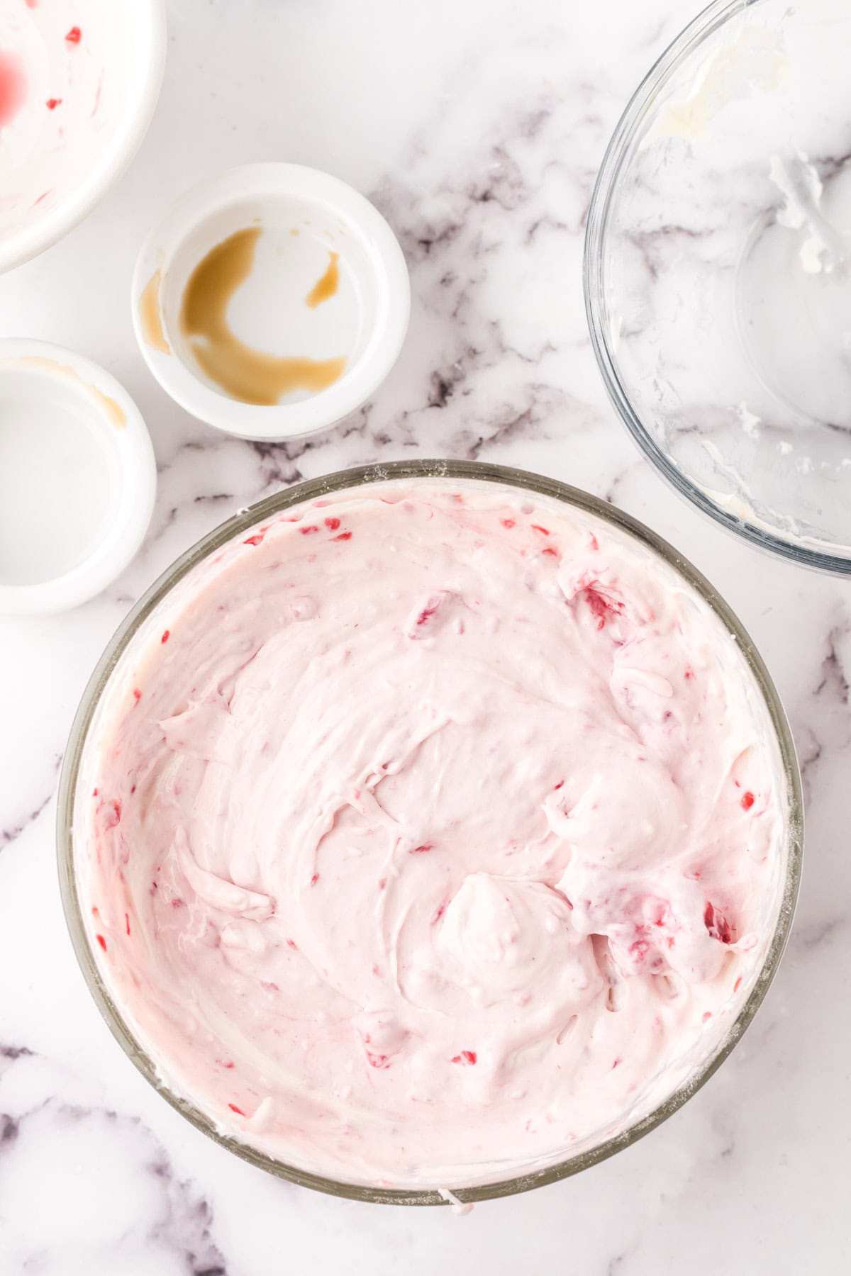 clear mixing bowl in the process of making raspberry cheesecake dip.