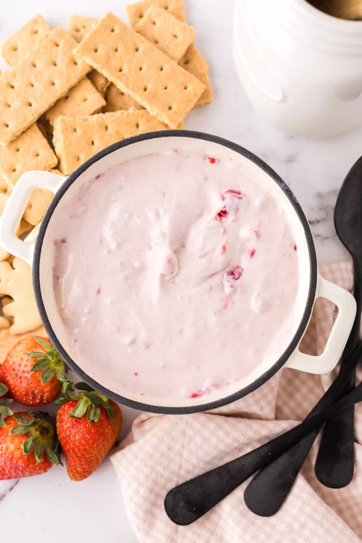 small bowl with crackers and berries around it with the raspberry cheesecake dip recipe inside.