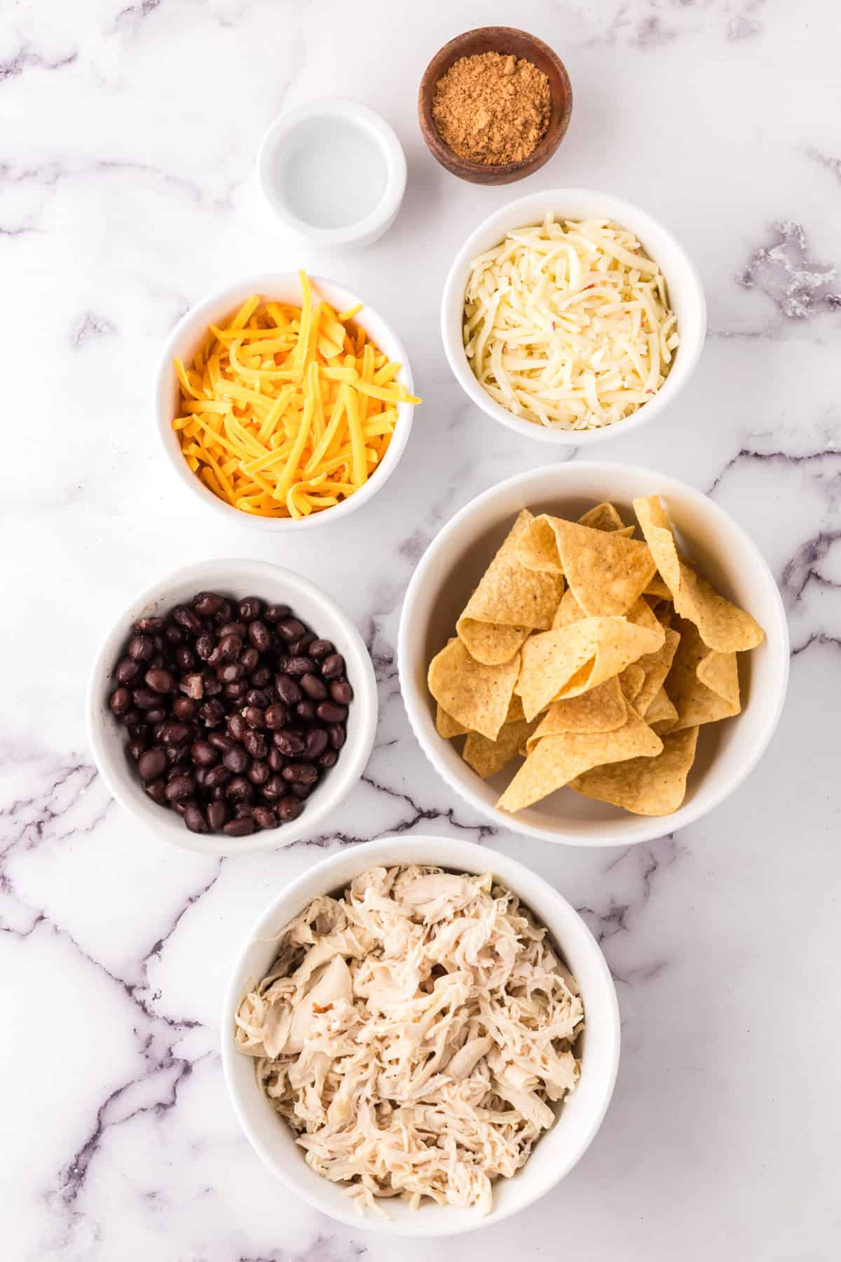 portion bowls each with raw ingredients to make the skillet chicken nacho recipe.