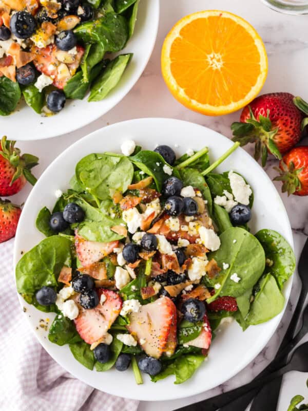 spinach and berry salad on a round white plate.