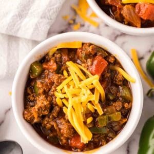 small bowl of texas chili with shredded cheese on top and jalapeños around.