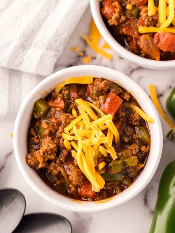 small bowl of texas chili with shredded cheese on top and jalapeños around.
