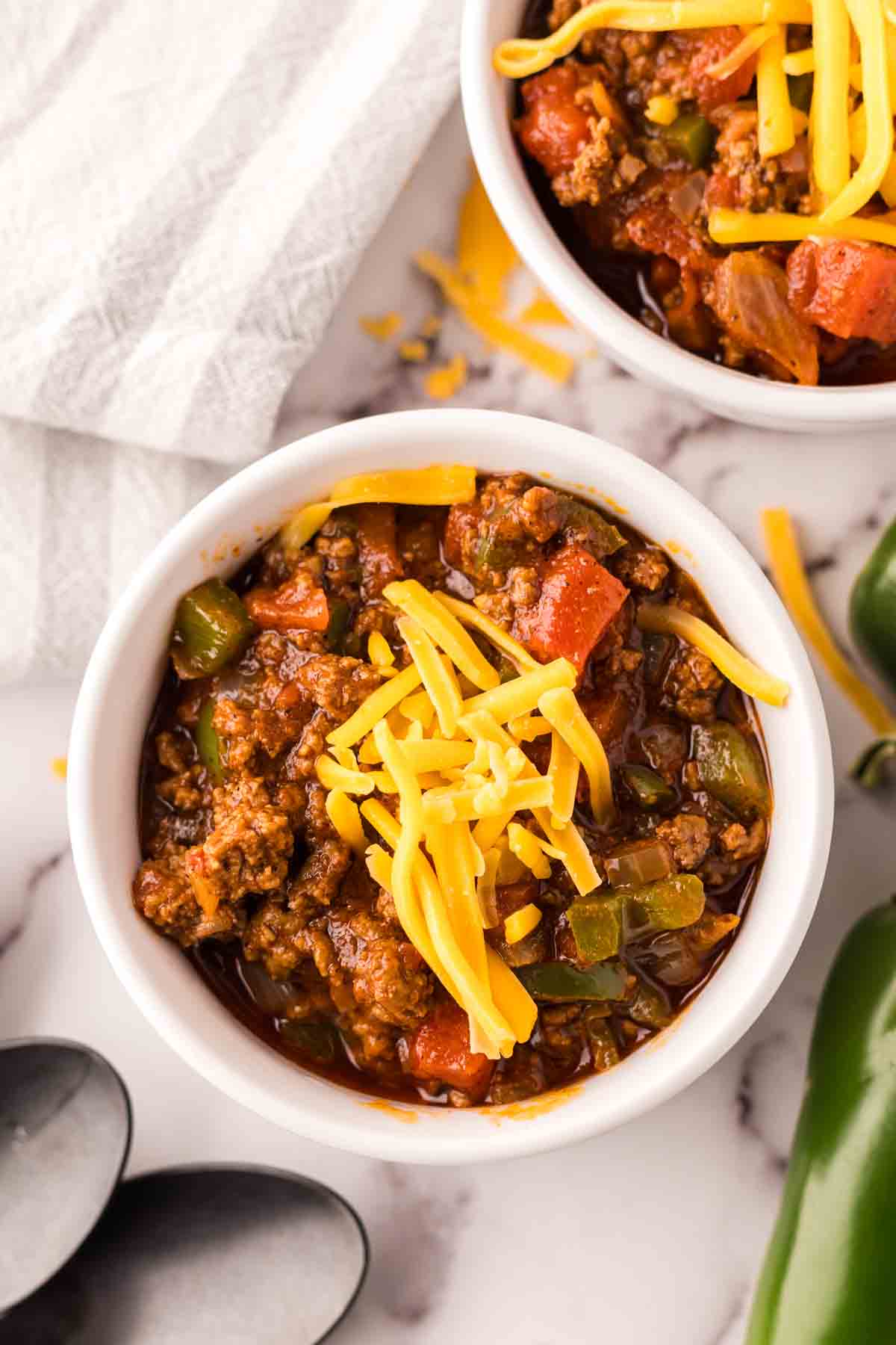 small bowl of texas chili with shredded cheese on top and jalapeños around.