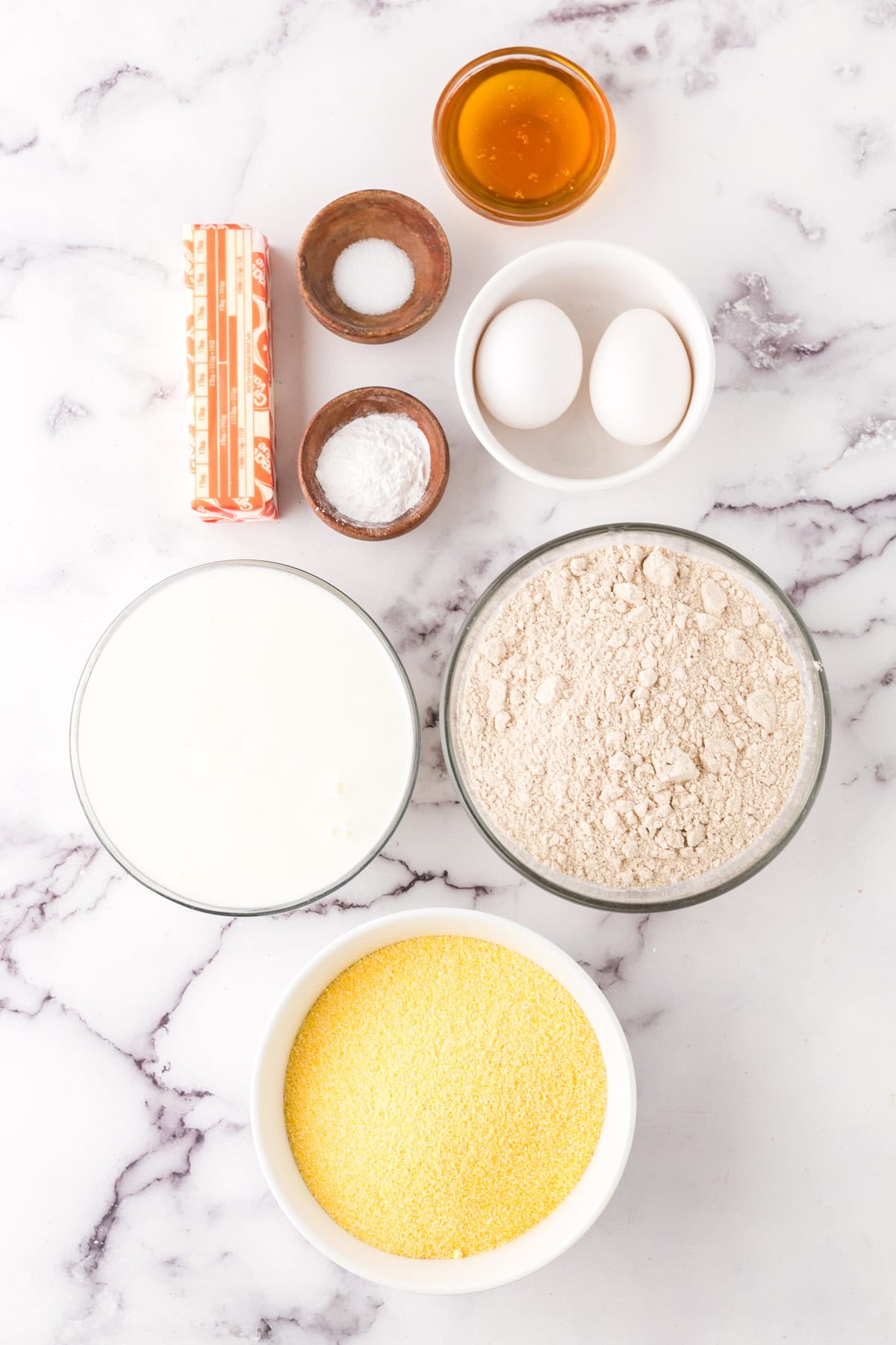 portion bowls each with raw ingredients to make whole wheat cornbread recipe.