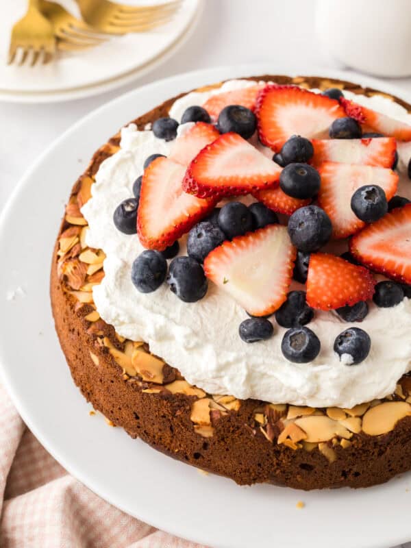 round whole wheat honey cake recipe with whipped topping and berries.