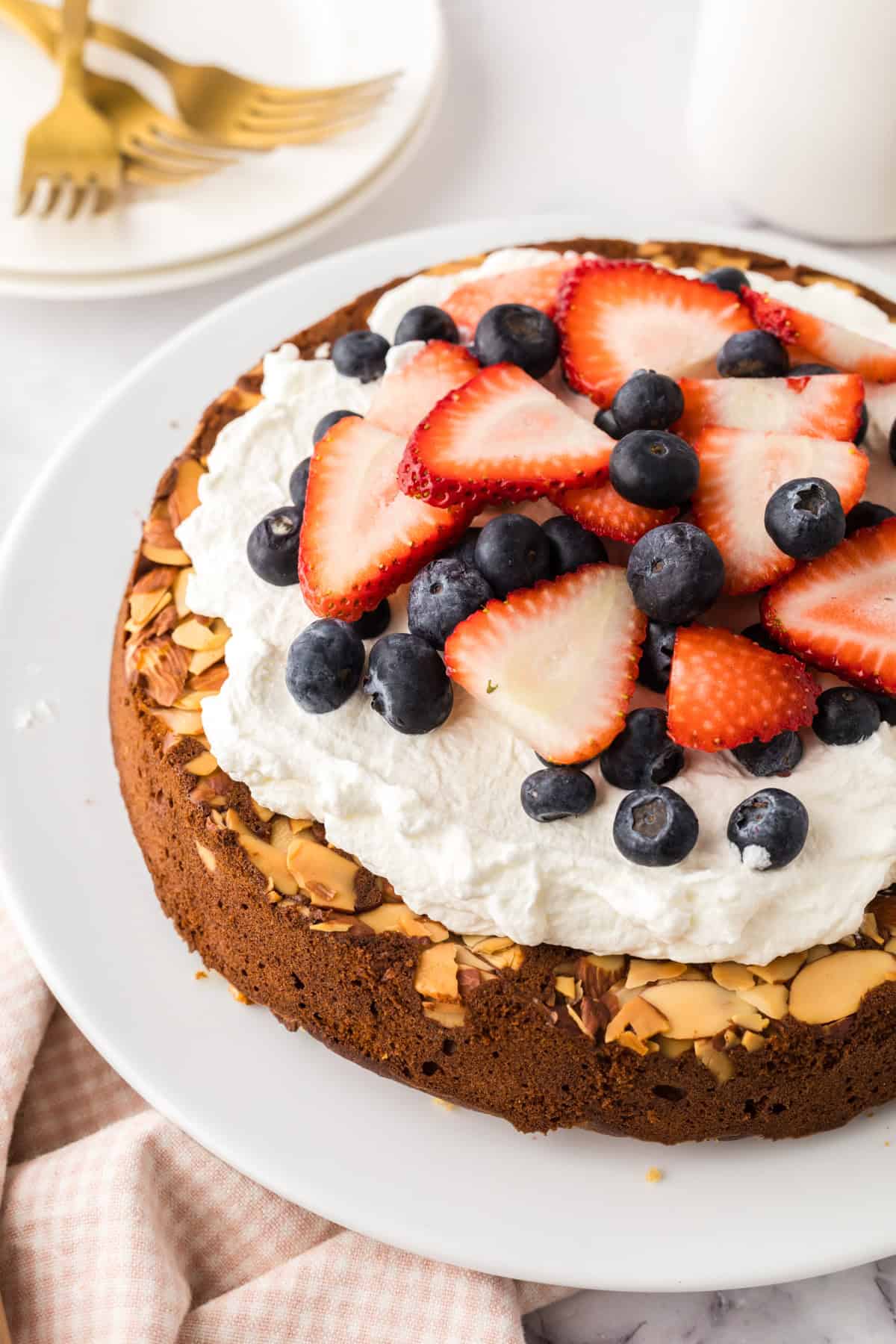 round whole wheat honey cake recipe with whipped topping and berries.