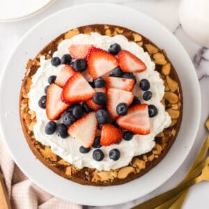 round whole wheat honey cake recipe with whipped topping and berries.