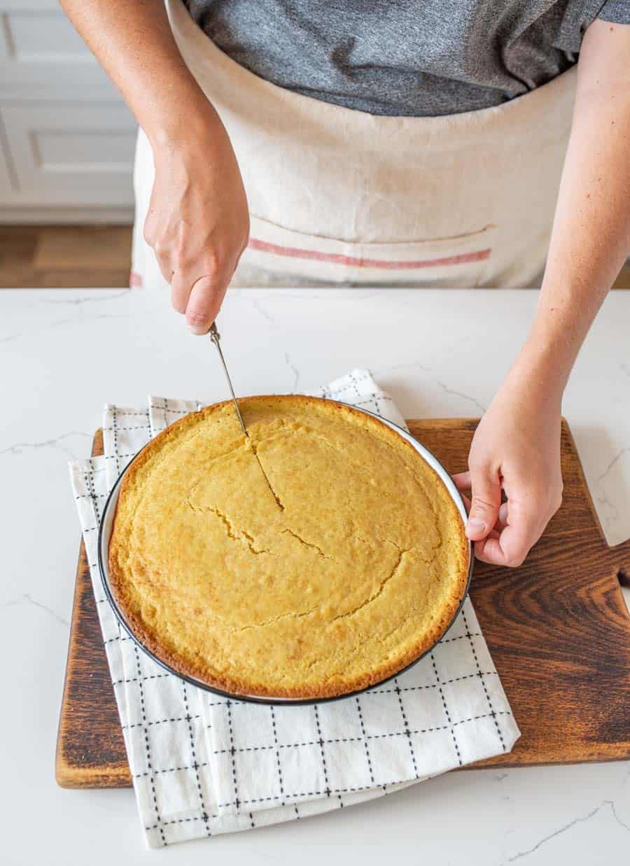 sourdough cornbread in a pie tin being sliced by a chef.