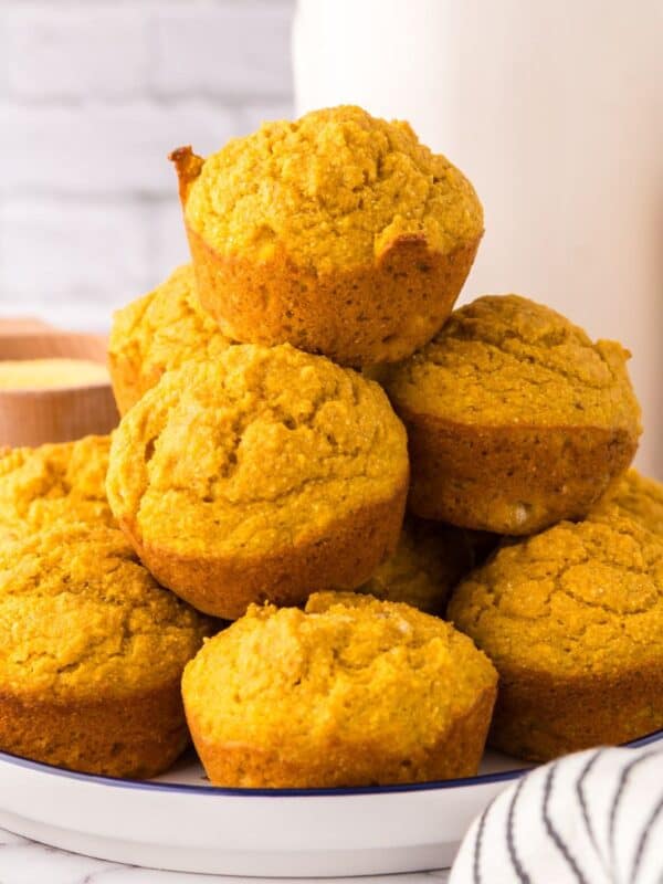 big stack of pumpkin cornbread muffins on a plate.