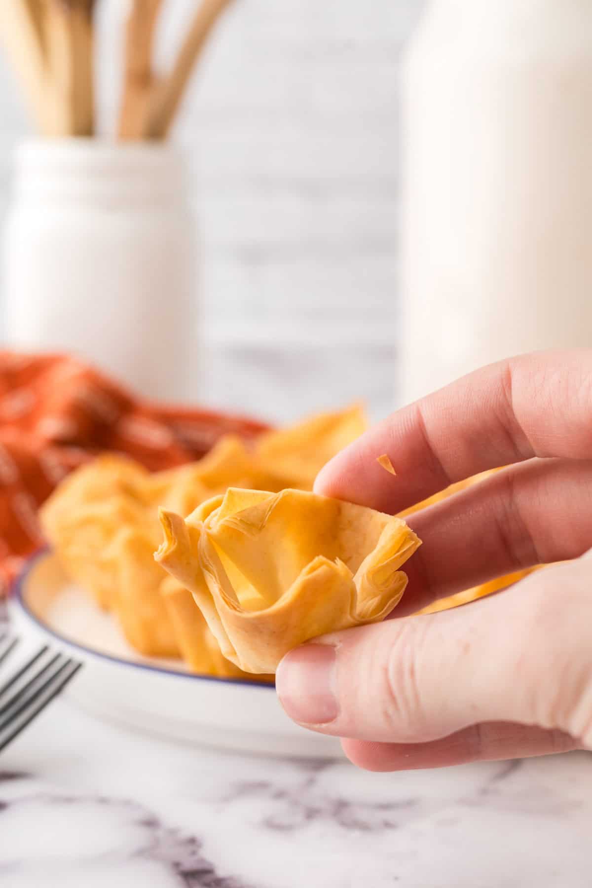 POV hand holding a homemade phyllo cup baked to a flakey golden brown.