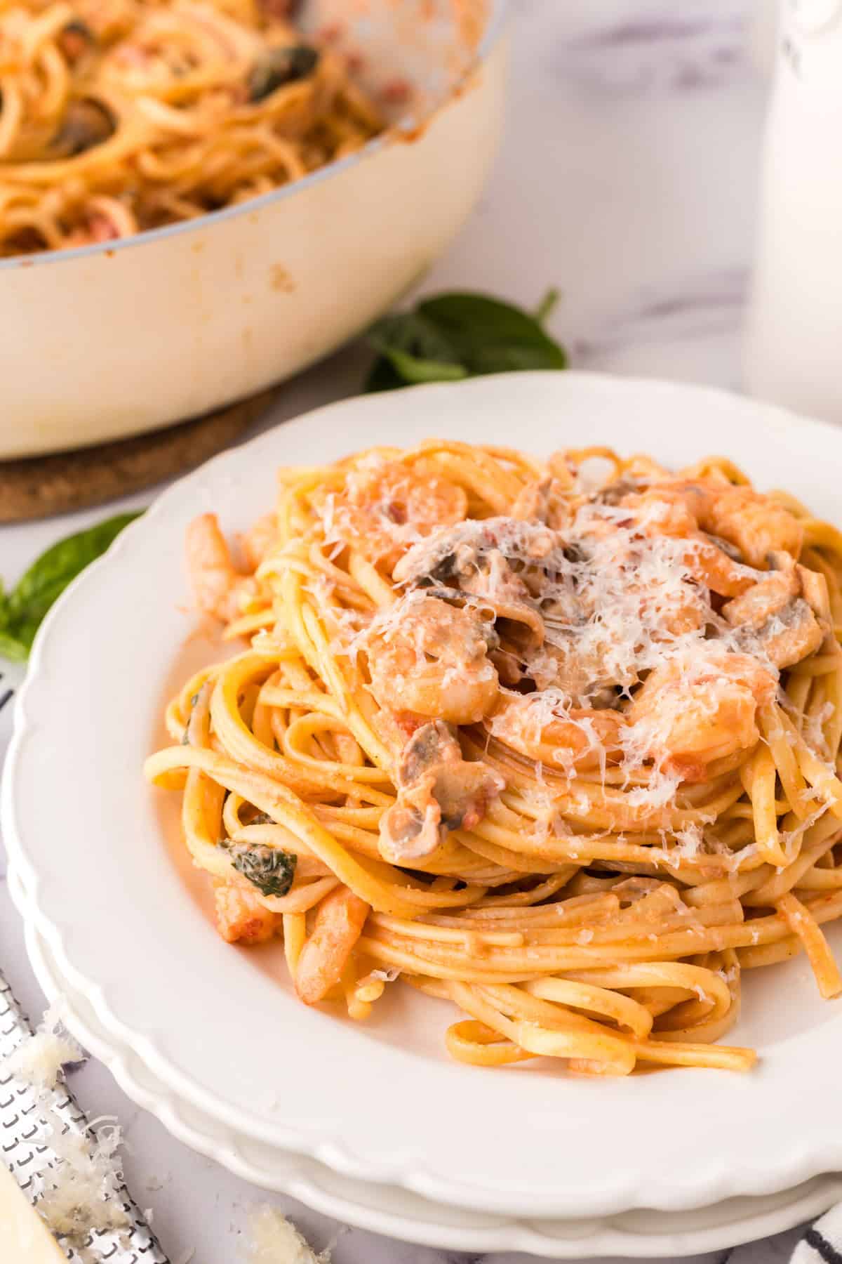 linguini rosa with shrimp on a round white plate.