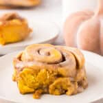 pumpkin cinnamon rolls on round white plates.