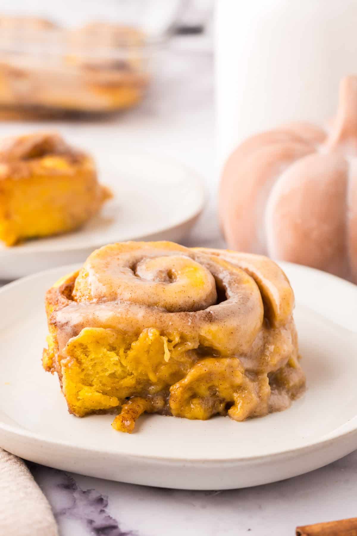 pumpkin cinnamon rolls on round white plates.