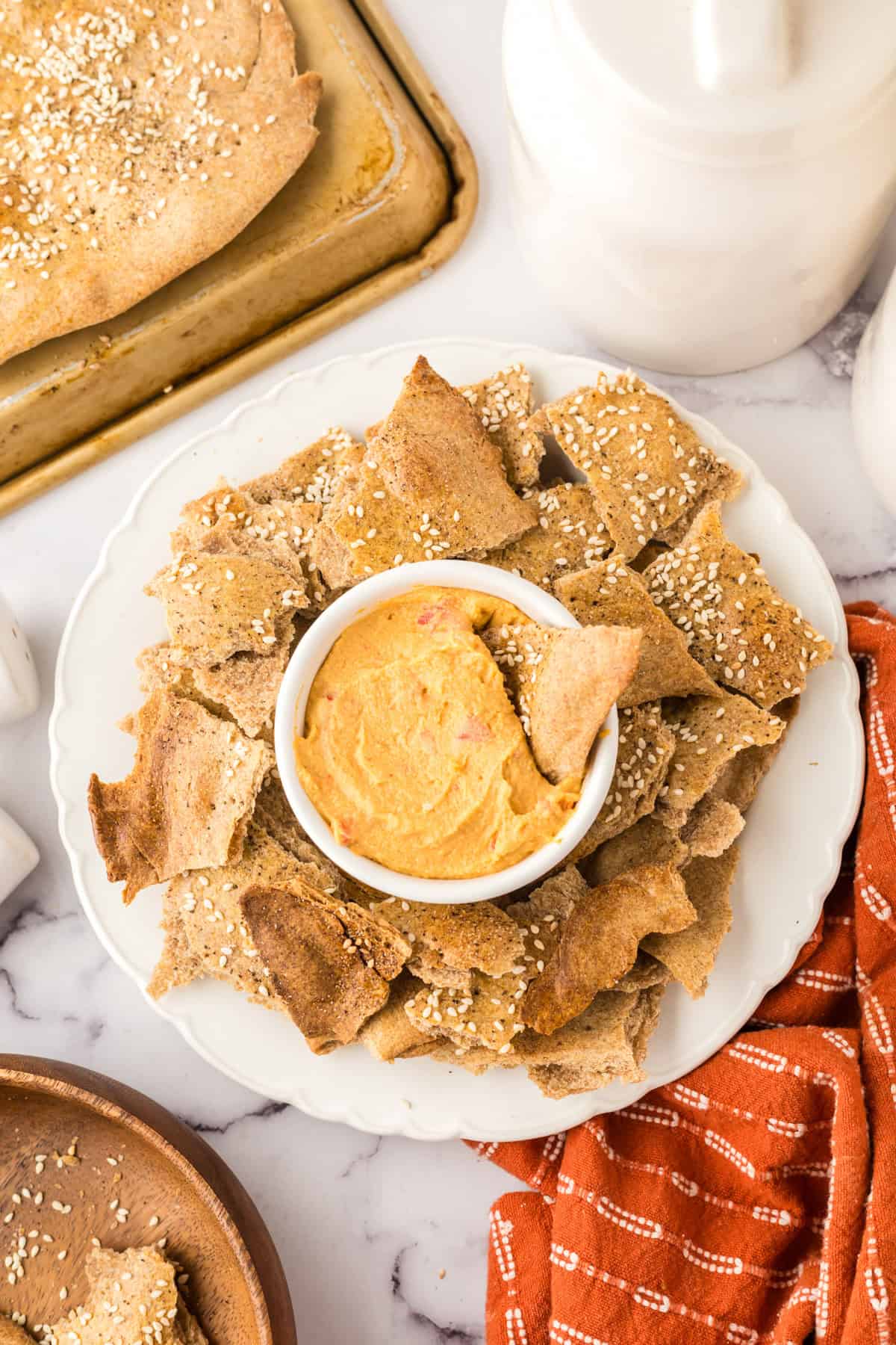 simple lavish bread crackers on a round plate with a bowl of dip in the middle.