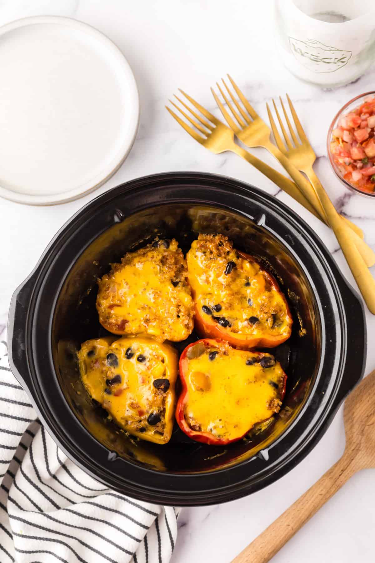 slow cooker bowl with four halved stuffed bell peppers.