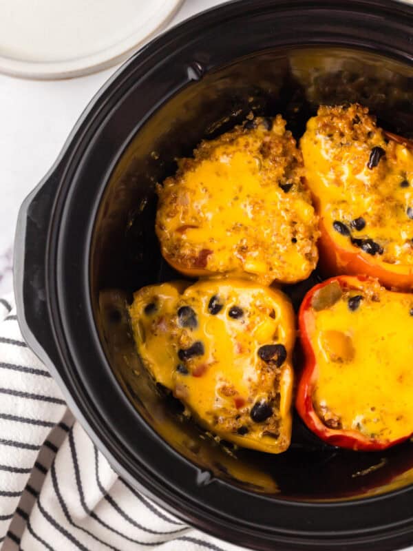 slow cooker bowl with four halved stuffed bell peppers.