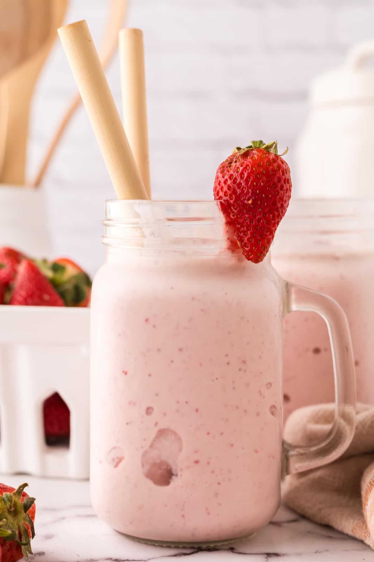 mason jar with a strawberry milkshake inside.