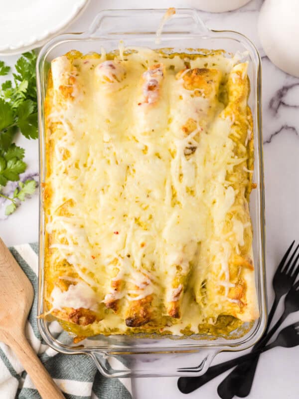 cheesy and gooey tomatillo ranch burritos in a clear casserole dish.