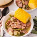 One pot farmstead wonder recipe served in a white bowl with corn on top next to black spoons.