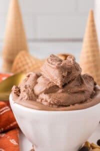 chocolate peanut butter ice cream scooped in a bowl with cones and a golden spoons around.