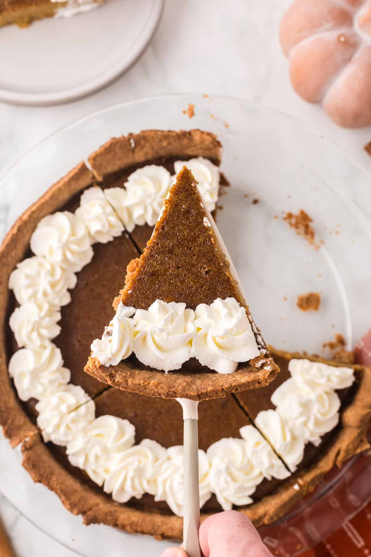 whole homemade healthy pumpkin pie recipe with one slice on a spatula.