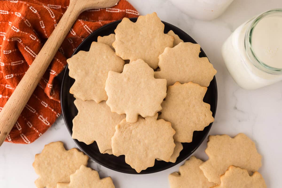 maple leaf shaped maple sugar cookies on a round black plate.