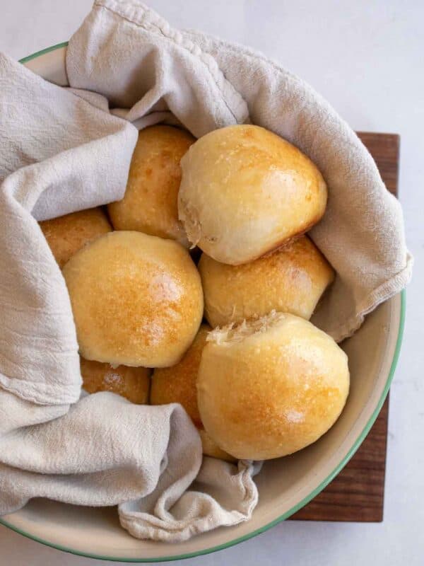 golden brown baked rolls in blue and white bowl with white towel.